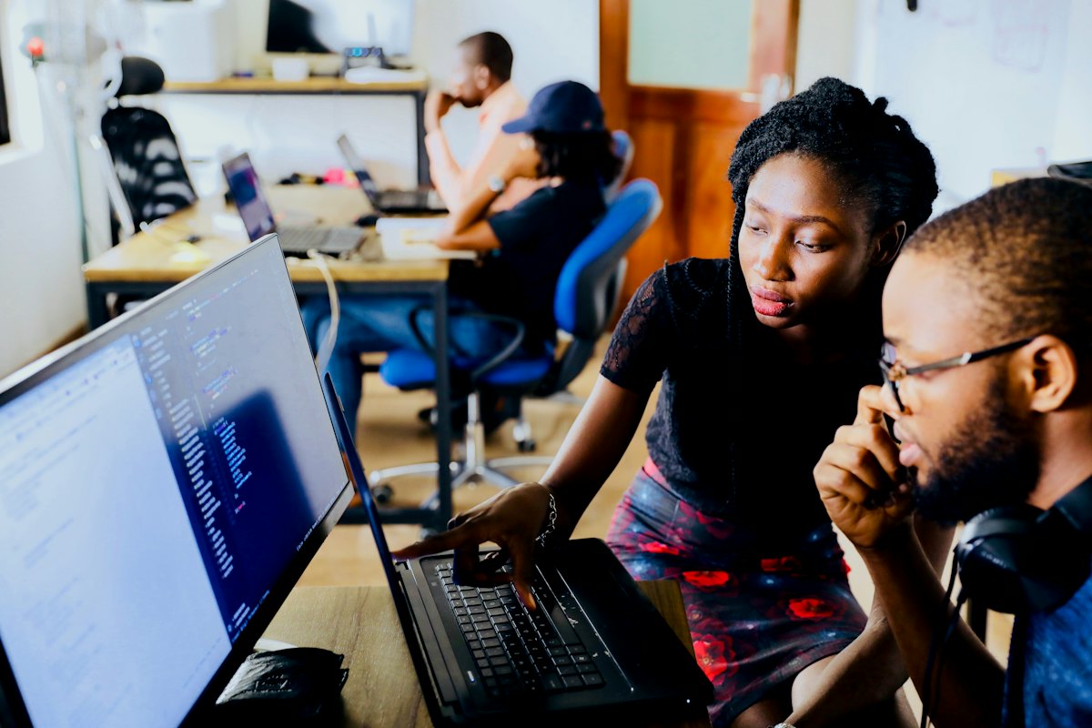 A university mentor guiding a student through coursework on a laptop